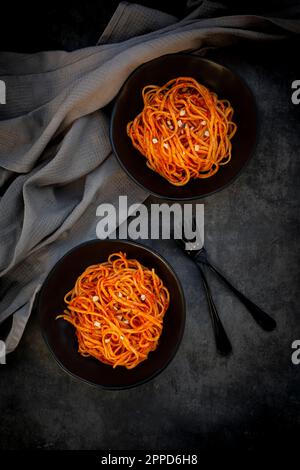 Studio de deux bols de linguine végétalienne avec sauce paprika aux amandes Banque D'Images