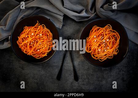 Studio de deux bols de linguine végétalienne avec sauce paprika aux amandes Banque D'Images