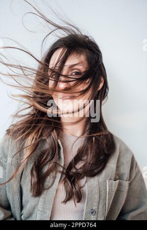 Jeune femme aux cheveux touffés devant le mur Banque D'Images