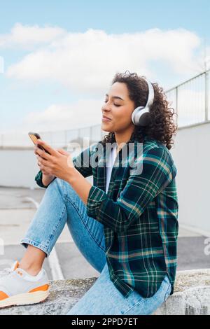 Bonne femme à porter un casque sans fil avec un smartphone Banque D'Images