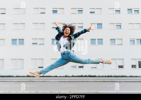 Une femme joyeuse sautant devant le bâtiment Banque D'Images