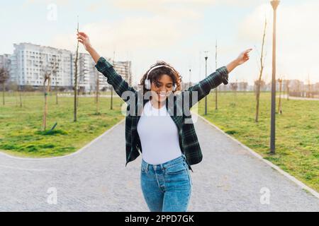 Une jeune femme heureuse portant un casque sans fil dansant sur le sentier Banque D'Images