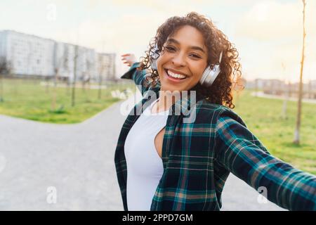 Une femme joyeuse dansant avec un casque sans fil Banque D'Images