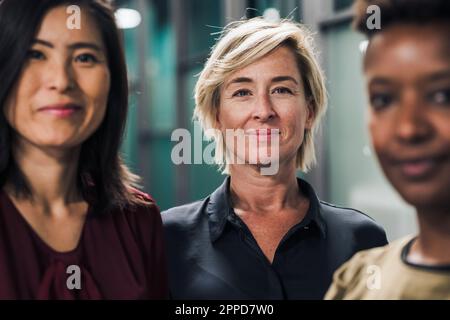 Femme d'affaires souriante debout avec ses collègues au bureau Banque D'Images