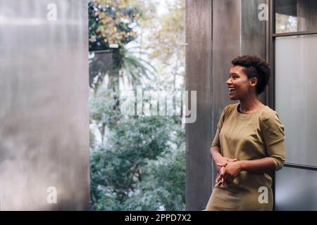 Bonne femme d'affaires regardant par la fenêtre au bureau Banque D'Images