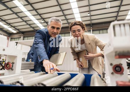 Ingénieurs examinant les machines en usine Banque D'Images