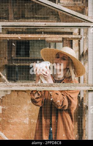 Fermier souriant tenant un oiseau debout dans un pigeonnier Banque D'Images