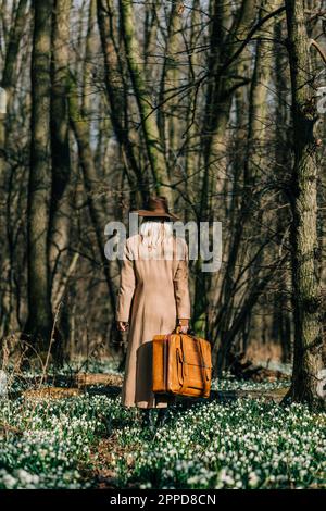 Femme avec valise à pied dans la forêt Banque D'Images