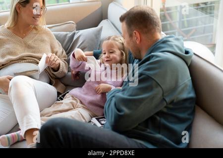 Parents montrant des photos d'échographie à leur fille à la maison Banque D'Images