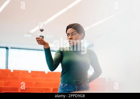 Jeune femme regardant le verre de l'heure dans l'auditorium Banque D'Images