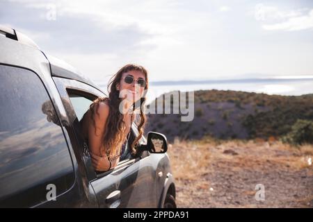 Happy young woman leaning out of car window Banque D'Images