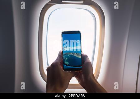 Homme prenant la photo par la fenêtre de l'avion Banque D'Images