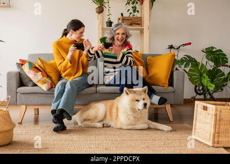 Bonne mère et fille jouant à des jeux vidéo à la maison Banque D'Images