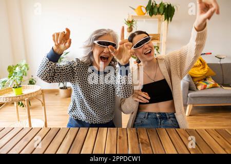 Mère et fille gaies portant des lunettes intelligentes s'amusant à la maison Banque D'Images