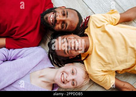 Bonne jeune femme avec des amis allongé sur le sol à la maison Banque D'Images