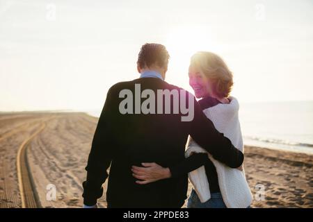 Femme mûre souriante avec homme marchant à la plage Banque D'Images