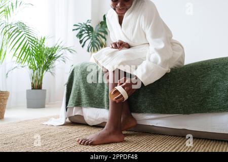 Jeune femme massant la jambe avec une brosse Banque D'Images