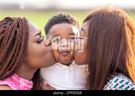 Jeunes femmes embrassant garçon sur joue Banque D'Images