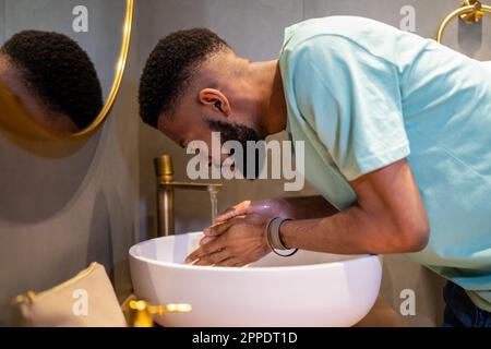 Fatigué endormi Afro-américain gars se lavant le visage avec de l'eau le matin Banque D'Images