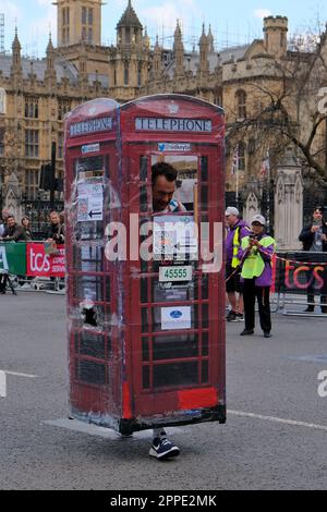 Londres, Royaume-Uni. 25th mars 2023. Un participant vêtu d'un coffret téléphonique rouge. Les coureurs de marathon sont presque à la fin de leur voyage pour atteindre la place du Parlement. Six heures après le début de l'événement, un flux régulier de coureurs passe toujours. Crédit : onzième heure Photographie/Alamy Live News Banque D'Images