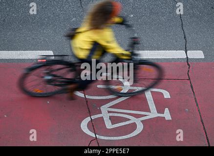 PRODUCTION - 20 avril 2023, Hesse, Francfort-sur-le-main : une cycliste féminine se trouve dans une piste cyclable rouge du centre-ville (prise avec une vitesse d'obturation plus longue). Sur 24 avril 2023, l'ADFC présentera les résultats de l'essai climatique 2022 de la bicyclette pour Hesse. L'enquête de l'automne 2022 vise à fournir des renseignements sur les municipalités de Hesse qui sont particulièrement adaptées aux vélos - et sur les endroits où il est nécessaire de rattraper leur retard. Dans le test de climat à vélo, les citoyens des municipalités allemandes sont interrogés sur leur convivialité à vélo. Photo: Arne Dedert/dpa Banque D'Images