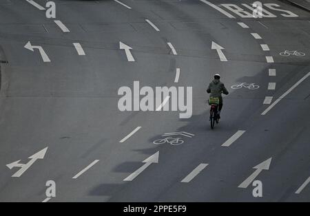 PRODUCTION - 20 avril 2023, Hesse, Francfort-sur-le-main : un cycliste est en ville sur une route à plusieurs voies marquée de flèches directionnelles et d'une piste cyclable. Sur 24 avril 2023, l'ADFC présentera les résultats de l'essai climatique 2022 de la bicyclette pour Hesse. L'enquête de l'automne 2022 vise à fournir des renseignements sur les municipalités de Hesse qui sont particulièrement adaptées aux vélos - et sur les endroits où il est nécessaire de rattraper leur retard. Dans le test de climat à vélo, les citoyens des municipalités allemandes sont interrogés sur leur convivialité à vélo. Photo: Arne Dedert/dpa Banque D'Images