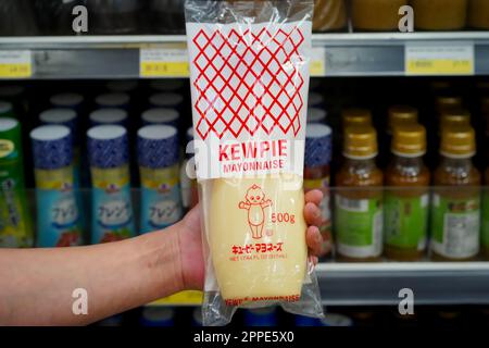 Tokyo, Japon - 15 avril 2023 : gros plan de mayonnaise de marque Kewpie de style japonais, tenue à la main dans une allée de supermarché locale avec des étiquettes de produits Banque D'Images