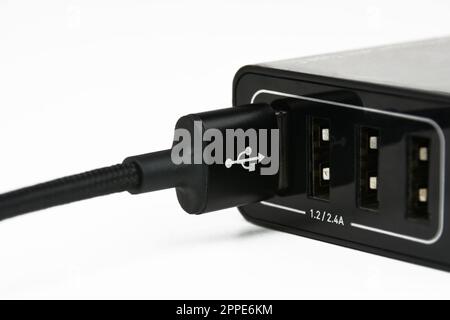 USB Un câble de chargement dans le port de chargeur de téléphone mobile sur fond blanc, concept d'équipement de téléphone mobile. Banque D'Images