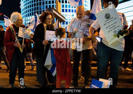 Tel Aviv, Israël. 22nd avril 2023. Un gamin donne une fleur aux membres de la famille endeuillée d’un soldat tombé lors d’une manifestation contre une révision judiciaire à tel Aviv. Crédit : SOPA Images Limited/Alamy Live News Banque D'Images