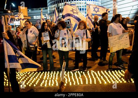 Tel Aviv, Israël. 22nd avril 2023. Les membres de la famille endeuillée tiennent des pancartes avec des photos de leurs proches, à côté de milliers de bougies « Yom Hazikaron » pour le jour du souvenir des soldats israéliens tombés et des attaques terroristes contre les victimes lors d'une manifestation de révision judiciaire à tel Aviv. Crédit : SOPA Images Limited/Alamy Live News Banque D'Images