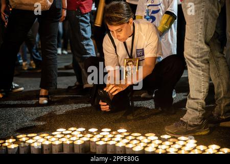 Tel Aviv, Israël. 22nd avril 2023. Les membres de la famille endeuillée tiennent des pancartes avec des photos de leurs proches, à côté de milliers de bougies « Yom Hazikaron » pour le jour du souvenir des soldats israéliens tombés et des attaques terroristes contre les victimes lors d'une manifestation de révision judiciaire à tel Aviv. Crédit : SOPA Images Limited/Alamy Live News Banque D'Images