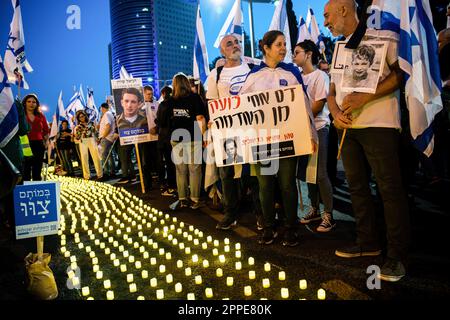 Tel Aviv, Israël. 22nd avril 2023. Les membres de la famille endeuillée tiennent des pancartes avec des photos de leurs proches, à côté de milliers de bougies « Yom Hazikaron » pour le jour du souvenir des soldats israéliens tombés et des attaques terroristes contre les victimes lors d'une manifestation de révision judiciaire à tel Aviv. Crédit : SOPA Images Limited/Alamy Live News Banque D'Images