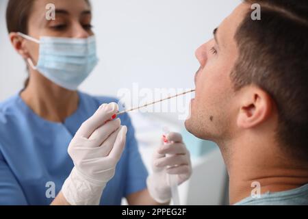 Médecin prenant l'échantillon pour le test d'ADN de l'homme en clinique Banque D'Images