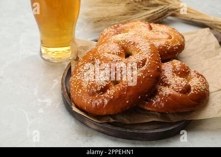 Bretzels savoureux, verre de bière et épis de blé sur table gris clair Banque D'Images