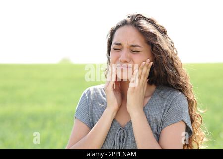 Femme souffrant de douleur à la mâchoire se plaignant dans un champ Banque D'Images