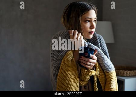 Femme en train de geler souffrant du rhume ou de la grippe ou ayant des difficultés avec le chauffage central Banque D'Images