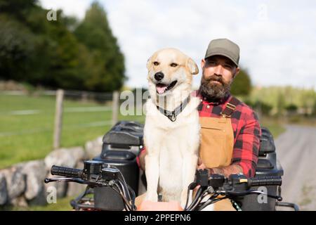 Agriculteur de sexe masculin avec chien à quatre roues Banque D'Images