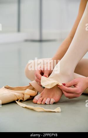 Ballerine mettant sur le ballet pointe chaussures assis sur le sol. Banque D'Images