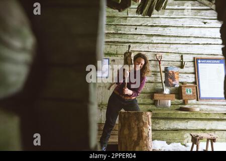 Femme hacher du bois dans un hangar Banque D'Images