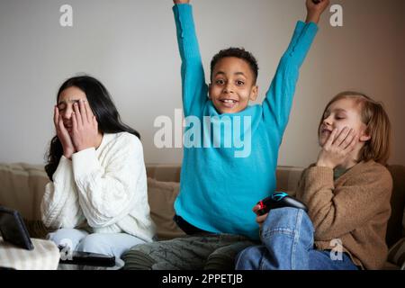 Les enfants jouent à des jeux vidéo à la maison et célèbrent Banque D'Images