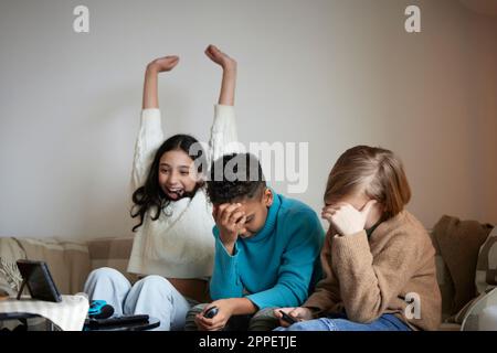 Les enfants jouent à des jeux vidéo à la maison et célèbrent Banque D'Images