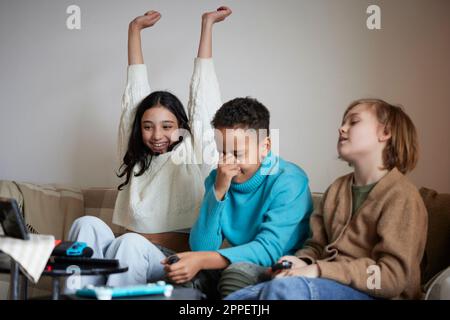 Les enfants jouent à des jeux vidéo à la maison et célèbrent Banque D'Images