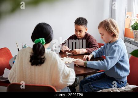 Filles et garçons jouant au scrabble à la table à manger Banque D'Images