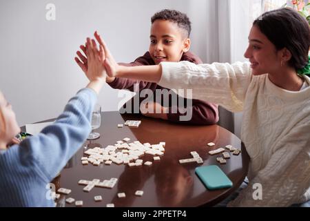 Filles et garçons jouant au scrabble à la table à manger Banque D'Images