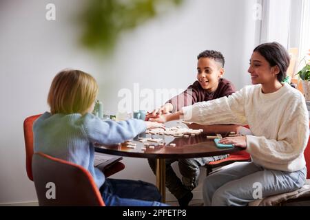 Filles et garçons jouant au scrabble à la table à manger Banque D'Images