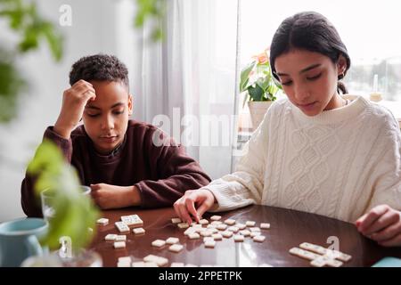 Fille et garçon jouant scrabble à la table à manger Banque D'Images