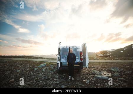 Femme souriante debout devant la camionnette de camping Banque D'Images