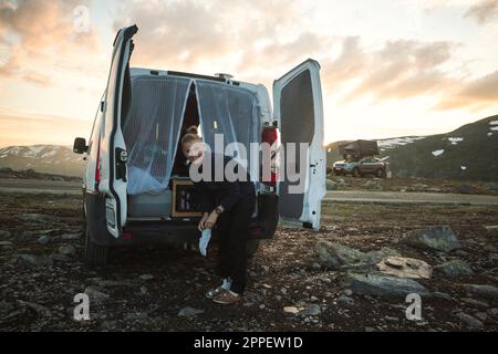Femme souriante debout devant la camionnette de camping Banque D'Images