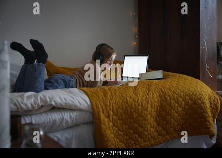Une fille fait ses devoirs avec un ordinateur portable dans sa chambre Banque D'Images