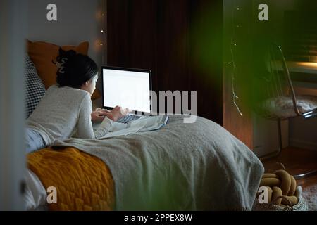 Une fille fait ses devoirs avec un ordinateur portable dans sa chambre Banque D'Images